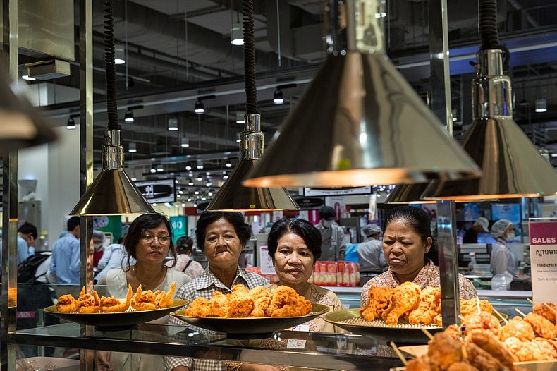 June 30, 2014 - Phnom Penh, Cambodia. A group of women look at fried chicken on display at Aeon Mall. Aeon Mall is Cambodia's first mega-mall, the inauguration was attended by the Cambodian Prime Minister Hun Sen, groups of residents from various economic backgrounds were trucked in to attend the event. © Nicolas Axelrod / Ruom
