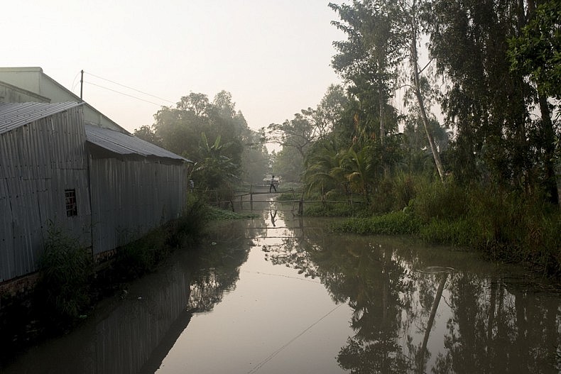 A man crosses a bridge over one of the many irrigation canals that run between the farmlands in one of Vietnams farming areas. Photo by Luc Forsyth.