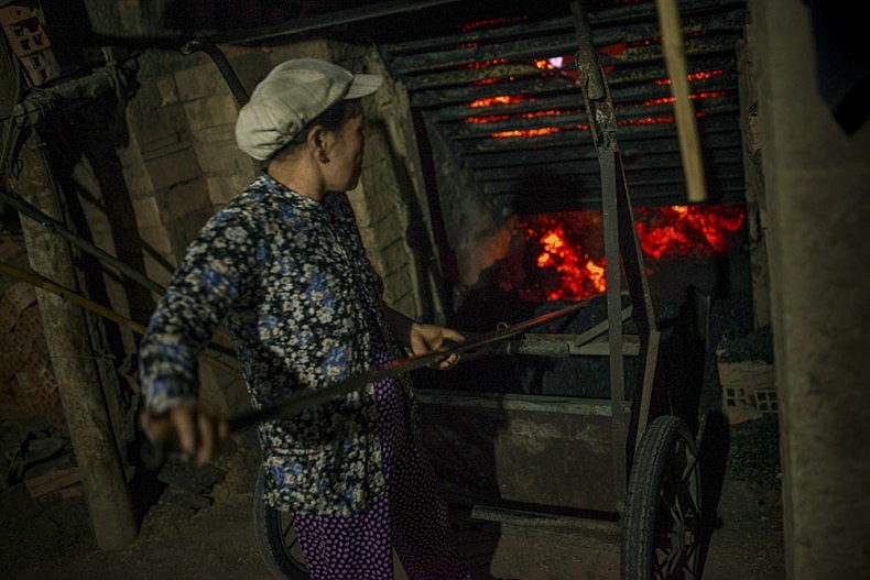 A worker stokes a fire under one of the factory's kilns. Photo by Luc Forsyth.