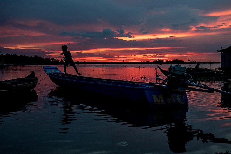 A boy runs along the gunnels of a fibre glass fishing boat in the village of Akol. Photo by Luc Forsyth