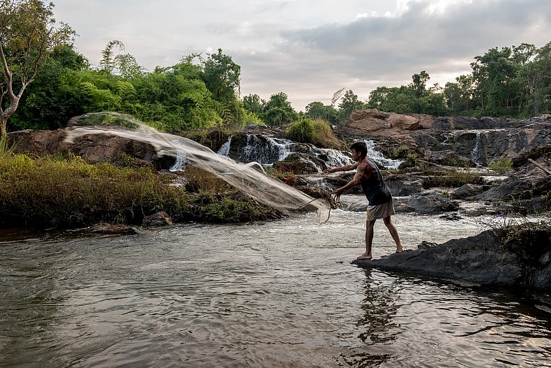 A man casts his fishing net into a pool of water above the Khone Phapheng waterfalls. Photo by Luc Forsyth.