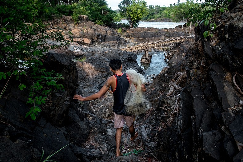 A fisherman walks through a rock field above the Khone Phapheng waterfalls. The rocks are exposed only in the dry season and will be under water when the monsoon rains fall and the Mekong rises to its full size.  Photo by Luc Forsyth.