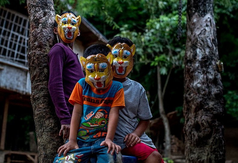 Children wear plastic masks in the village of Khoc Kham. With the introduction of affordable outboard motors, the villagers, who have no road access to the outside world, can trade with nearby villages. Photo by Luc Forsyth.