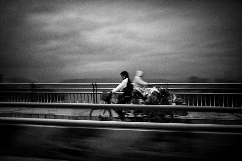 Two locals cross each, early morning, on a  bridge spanning the Lancang (Mekong) in Xishuangbanna, Yunan, China. Photo by Gareth Bright.