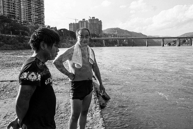 Two locals stand on a jetty that extends into the river, after swimming in the Lancang (Mekong) river in Xishuangbanna, China. Photo by Gareth Bright.