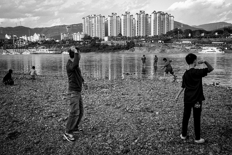 Tourists and locals gather to skips stones and play along the Lancang (Mekong) river in Xishuangbanna, Yunan, China. Photo by Gareth Bright.