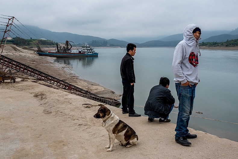Sand dredgers try to keep warm before the day's work begins in Simaogang. Photo by Luc Forsyth.