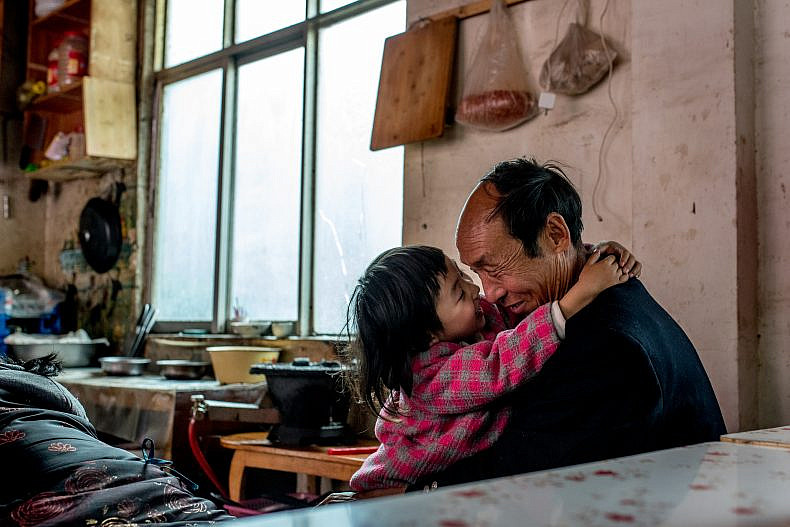 A father plays with his daughter in a small restaurant in the village of Xialuoga. Photo by Luc Forsyth.