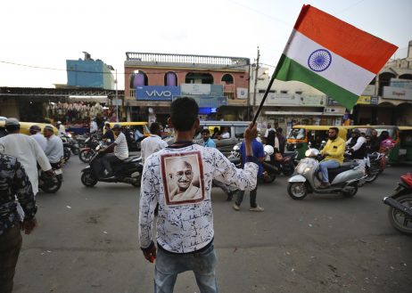 Un indú sostiene la bandera nacional y muestra un retrato de Gandhi en una protesta contra "la segunda muerte de Gandhi"